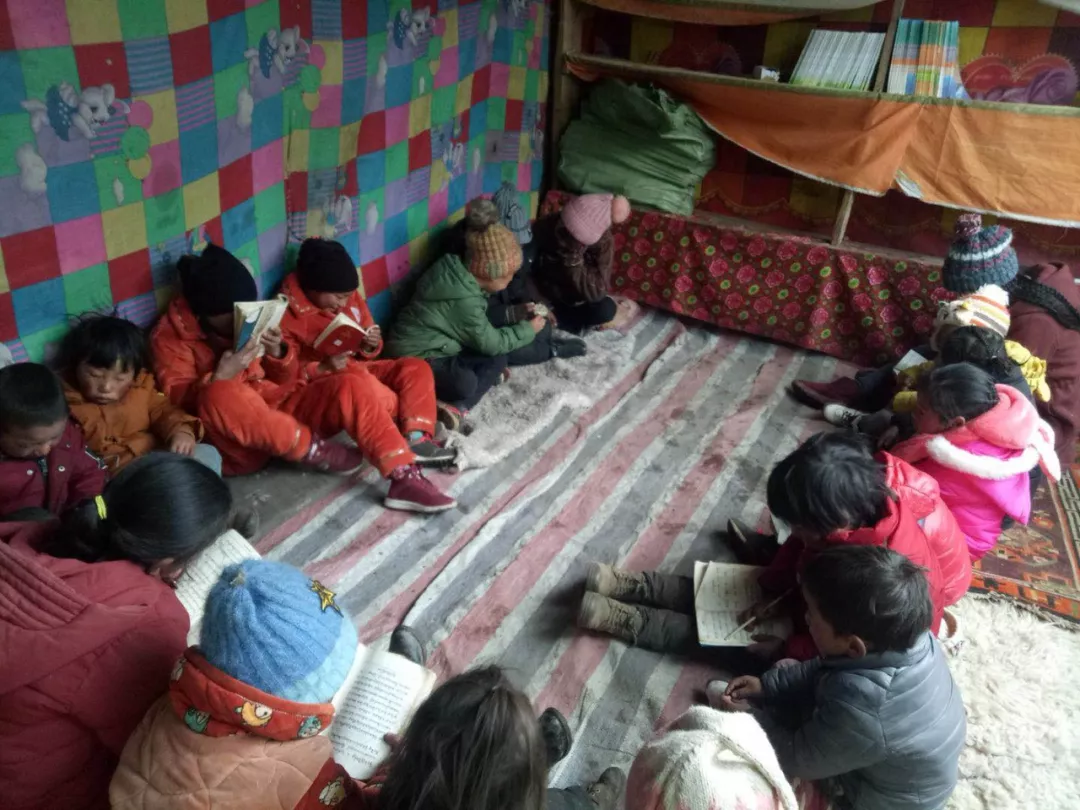 玉隆拉措希望学校的孩子们坐在尼龙布上面学习